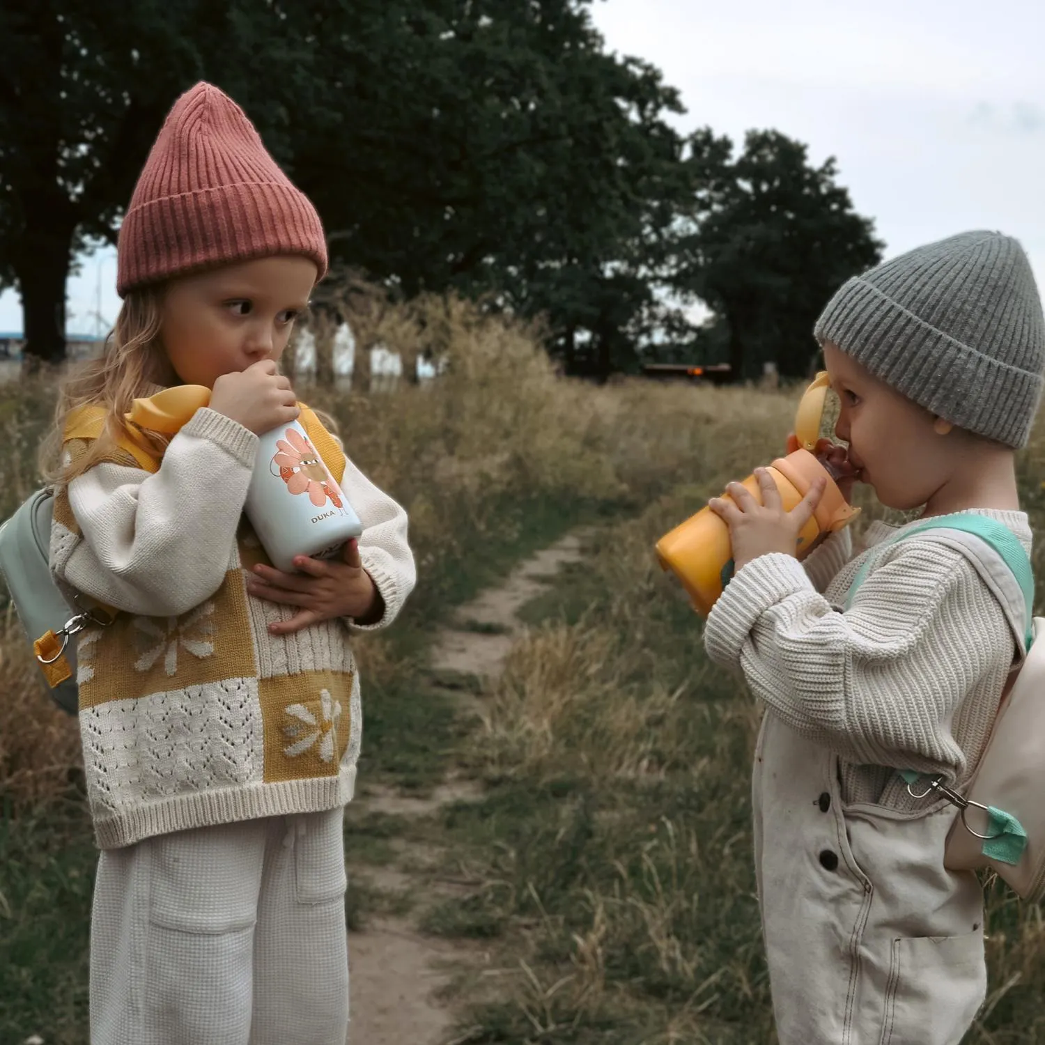image dziecięcy kubek, dwóch dzieci, sweter z motywem, zestaw ubrań dzianinowych, butelka na mleko / napój