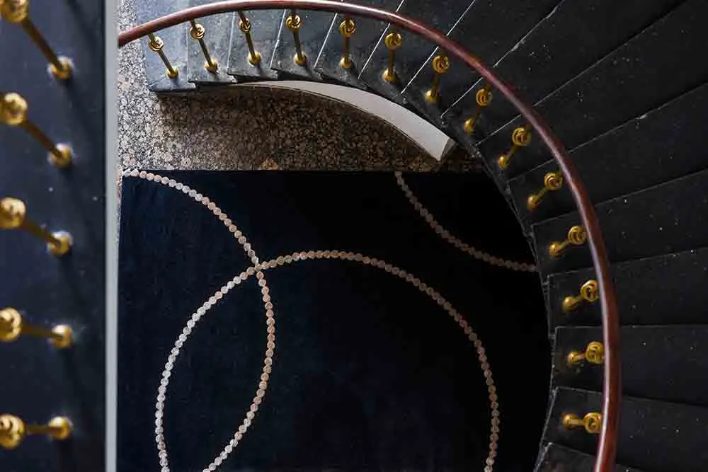 spiral staircase, curved stairs, black carpet, gold railing, round pattern